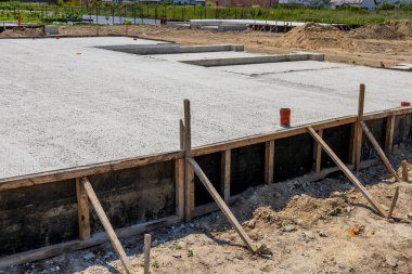 Workers pour cement to create a solid foundation slab for a new house in a residential development area under construction.