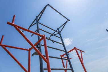 A horizontal training bar structured for fitness activities stands under a clear blue sky in a park, inviting athletes to engage in outdoor workouts.