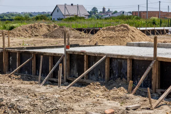 Workers pour cement to create a solid foundation for a new house in a developing neighborhood surrounded by nature.