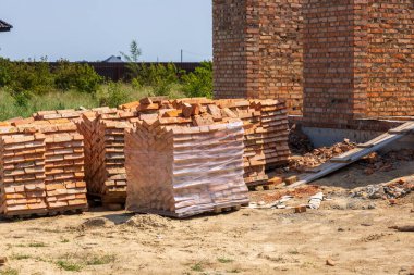 Tuğlalar temiz gökyüzünün altında büyüyen bir mahallede ev inşa etmek için düzgün bir şekilde istiflenir..