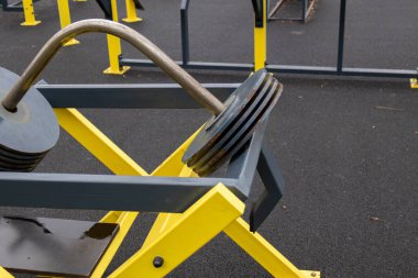 Ağır plakalar, halka açık bir spor salonunda güneş ışığı altında dayanıklılık eğitimi için tasarlanmış dayanıklı bir spor iskeletinin üzerinde dinleniyor..