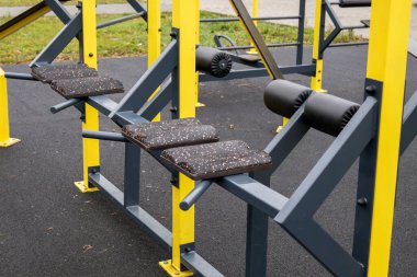 Ağır iş antreman yapıları parkta boş duruyor. Çimenler ve patikalar ekipmanın etrafını sarmış. Güç eğitim faaliyetleri için ideal.