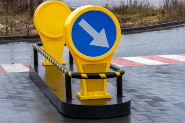 Mavi oklu sarı trafik işaretleri gün ışığında düz bir yolda ilerlemek için rehberlik sürücüleri.