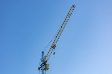 Sıcak, güneşli bir günde mavi gökyüzüne ulaşan hareketli bir şehir manzarası üzerinde yüksek bir vinç kuleleri..