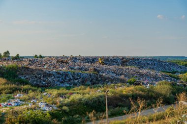 Çöp dağları, her gün çevreyi etkileyen kirlilik ve atıkları hatırlatan ufukta belirgin bir şekilde yükseliyor..