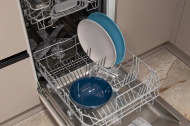 Bulaşıklar mutfakta bulaşık makinesinin içinde düzenlenir. Tabaklar, kaseler ve bardaklar görünür ve temizlik için hazırdır..