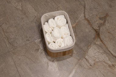 Yumuşak beyaz havlular düzgünce katlanır ve bir sepete konur. Zarif mermer zeminin rahatlatıcı hissini arttırır..