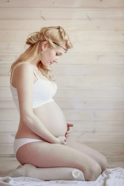 Красивая беременная блондинка в светлой комнате — стоковое фото