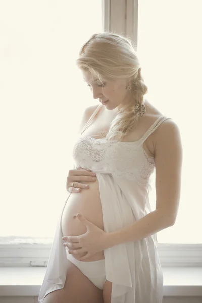 Красивая беременная блондинка в светлой комнате — стоковое фото