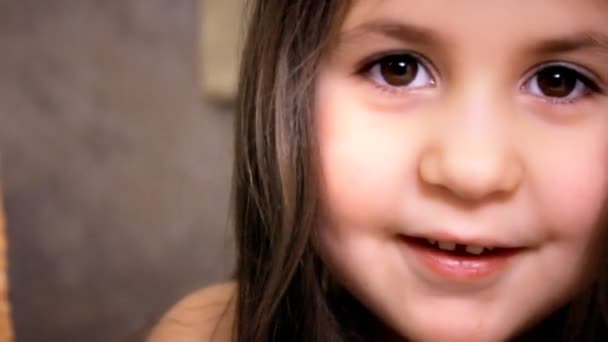 Little Girl Face Close Up With Long Hairs está mirando en la cámara y sonriendo. Pequeña hermosa chica degustar chocolates con gusto . — Vídeo de stock