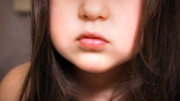 Little Girl Face Close Up With Long Hairs está mirando en la cámara y sonriendo. Pequeña hermosa chica degustar chocolates con gusto . — Vídeo de stock