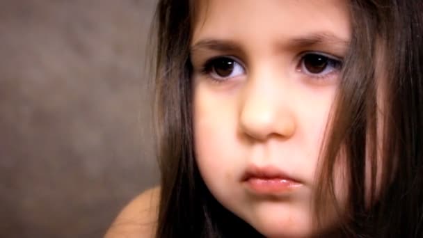 Little Girl Face Close Up With Long Hairs está mirando en la cámara y sonriendo. Pequeña hermosa chica degustar chocolates con gusto . — Vídeo de stock