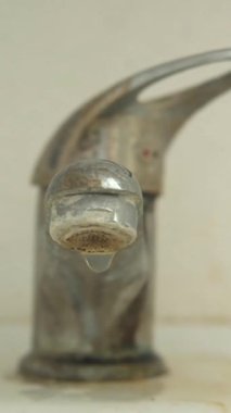 Eski, kirli, sert bir su tabakası damlayan ya da sızdıran bir musluk. Yüksek kalite 4k görüntü