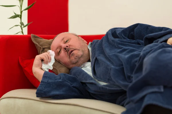 Hombre enfermo acostado en el sofá con fiebre alta — Foto de Stock