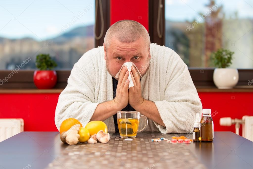 Sick man suffering cold and winter flu virus drinking tea