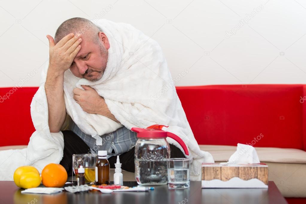 Sick  man wearing pajama suffering cold and winter flu virus having medicine