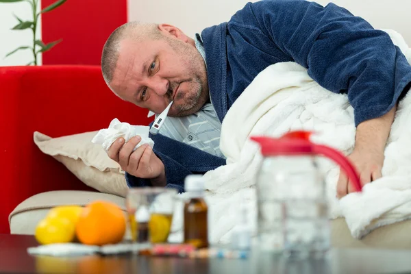 Zieke man in bed met drugs en groenten op tafel — Stockfoto