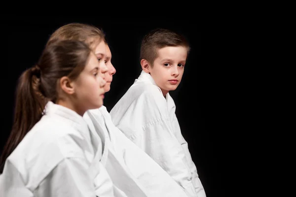 Dzieci w kimono siedzi na tatami na seminarium sztuk walki. Selektywne focus — Zdjęcie stockowe