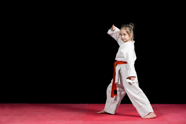 Kleine meisje praktijk karate geïsoleerd op zwart — Stockfoto