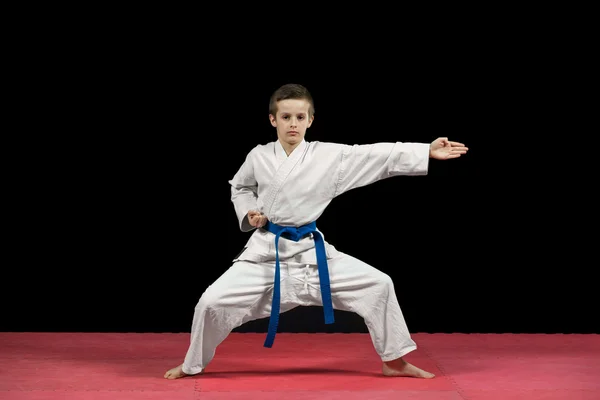 Retrato de un niño de karate en kimono listo para luchar aislado sobre fondo negro — Foto de Stock