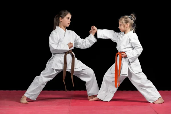 Dos chicas en kimono están entrenando ejercicios emparejados karate —  Fotos de Stock
