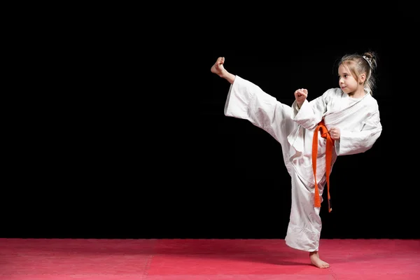 Kleine meisje praktijk karate geïsoleerd op zwart — Stockfoto