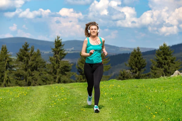 Kız ile çim sahada dağlarda izinde yaz güneşli bir günde koşu.