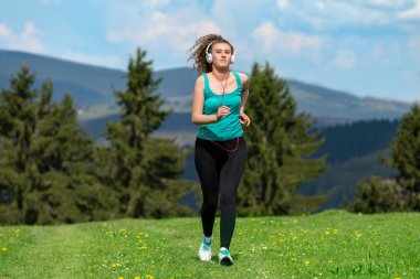 Kız ile çim sahada dağlarda izinde yaz güneşli bir günde koşu.