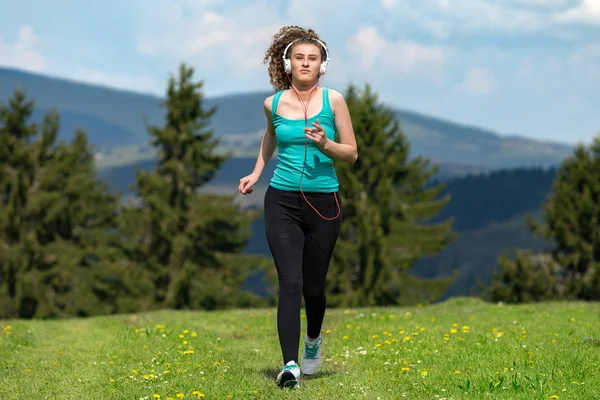Kız ile çim sahada dağlarda izinde yaz güneşli bir günde koşu.