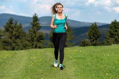 Kız ile çim sahada dağlarda izinde yaz güneşli bir günde koşu.