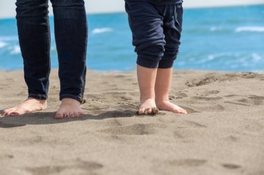 Anne ve çocuk bir kumsalda yürüyen