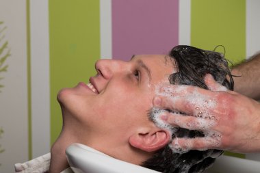 Erkek müşterinin saçını kuaförde yıkattığı portre.