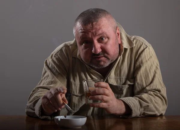 Alcoholismo: retrato de un hombre solitario y desesperado bebiendo alcohol y fumando cigarrillos — Foto de Stock