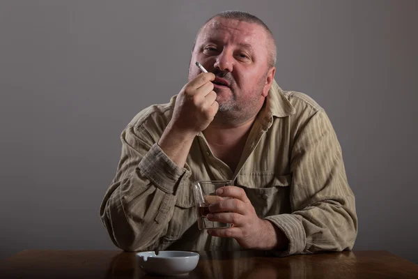 Alcoholismo: retrato de un hombre solitario y desesperado bebiendo alcohol y fumando cigarrillos — Foto de Stock