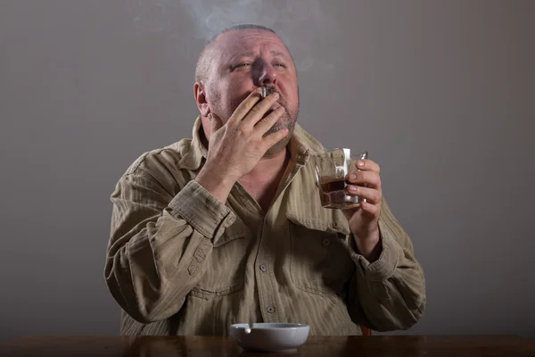 Alcoholismo: retrato de un hombre solitario y desesperado bebiendo alcohol y fumando cigarrillos — Foto de Stock
