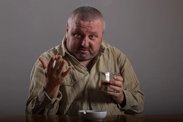 Alcoholismo: retrato de un hombre solitario y desesperado bebiendo alcohol y fumando cigarrillos — Foto de Stock