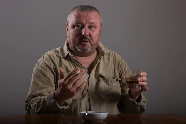 Alcoholismo: retrato de un hombre solitario y desesperado bebiendo alcohol y fumando cigarrillos — Foto de Stock