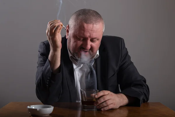 Hombre de negocios con un vaso de whisky y cigarrillo — Foto de Stock