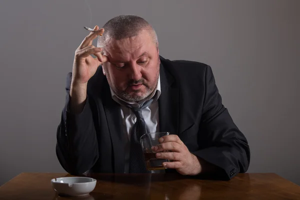 Hombre de negocios con un vaso de whisky y cigarrillo — Foto de Stock