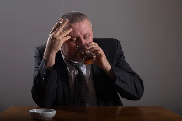 Uomo d'affari con un bicchiere di whisky e sigaretta — Foto Stock