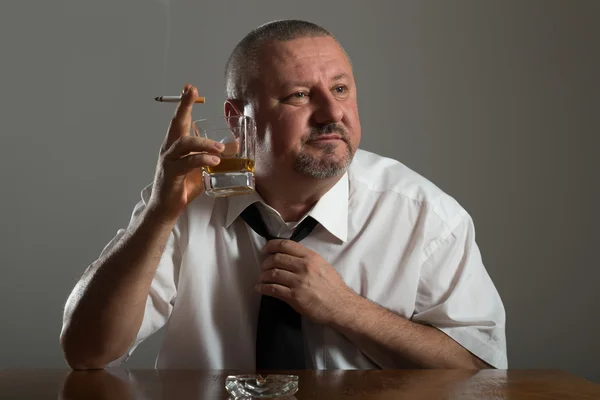 Businessman drinking alcohol and smoking cigarette