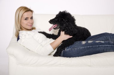 Siyah bir fino köpeği ile beyaz kanepede yatan kadın.