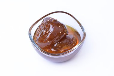 Beyaz zemin üzerinde bir cam kabın içinde ev yapımı incir reçeli