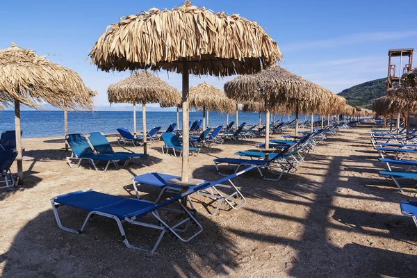 Straw umbrellas and sunbeds on a sandy beach, Corfu, Greece — Stock Photo, Image