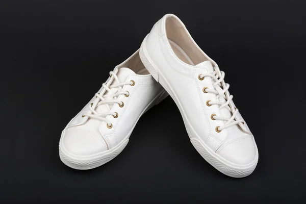 Sapatos esportivos brancos femininos no fundo escuro — Fotografia de Stock