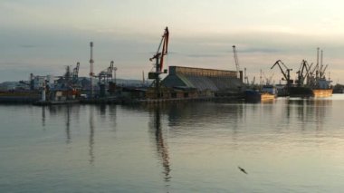 Bulgaristan 'ın Karadeniz kıyısındaki Burgaz limanında gün batımı. Gün batımında vinç siluetleri.