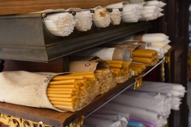 Ortodoks kilisesindeki ahşap raflardaki balmumu ve beyaz mumların yakın plan görüntüsü inanç, din ve ruhani geleneği yansıtıyor..