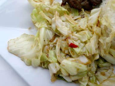 Fry lahana, balık sosu ve kızarmış domuz eti ile tavada kızartılmış lahana beyaz tabak içinde karıştırın.