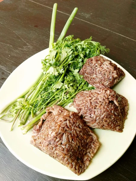 Khao kan chin, Local north thailand food of rice that is mixed with pork blood and steamed inside a banana leaf, serving with cucumber, onions and fried, dried chillies. Still life style. — Stock Photo, Image