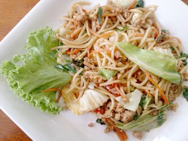 Ahşap masa üzerinde beyaz tabak acılı spagetti